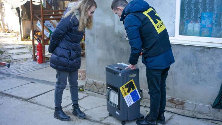 An IRC staff person shows Nataliia a heating device